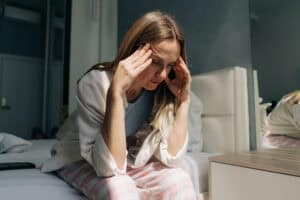 A middle-aged woman sitting at home holds her hands on her temples Headache womens health hormonal levels Financial crisis - Engelhardt Rechtsanwaltskanzlei - Engelhardt Rechtsanwaltskanzlei
